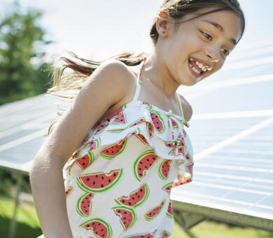 Girl running beside solar panels